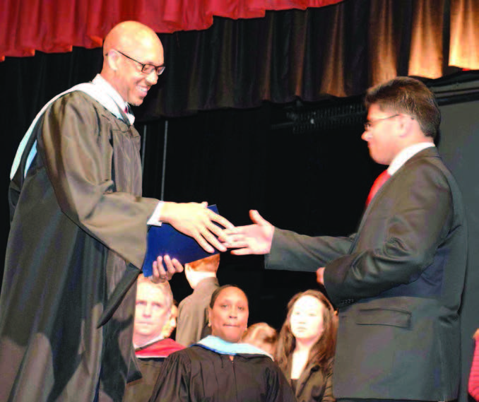 Shiv receiving the folder from his school Principal, Mr. Raymond William.