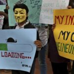 An activist wears a mask as he holds a placard during a demonstration supporting net neutrality, in Bangalore – AP