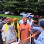 Inauguration. Dr. Surinder S Gill (back to camera) passing over a pair of scissors for Dr. Kirpal Kaur, Trustee of Gurudwara Sikh Association of Baltimore and Manjit Singh GK, President, DSGPC, to inaugurate the school. Seen are community leaders who helped in raising the school which included Gurudwara Sikh Association of Baltimore President Jeet Singh and Chairman K. K. Sidhu.