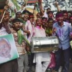 Supporters of the Janata Dal (United) party celebrate after learning of the initial election results at their party office in Patna