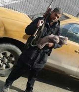 Suspected ISIS terrorist Abu Rumaysah, who was born as Siddhartha Dhar holding his newborn son in one hand and an AK-47 assault rifle in the other. (File Photo)