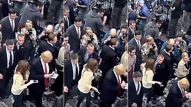 In new footage, the reporter (in cream jacket) is seen alongside Mr Trump before being held back
