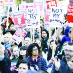 Protesters hold signs during a protest the election of President-elect Donald Trump in downtown Seattle on November 9, 2016
