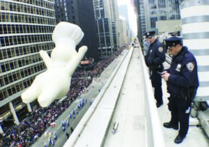New York Police Department officers stand watch from a building as a float proceeds high above spectators along Sixth Avenue during the 89th Macy’s Thanksgiving Day Parade in Manhattan on November 26, 2015.Photo/ Carlo Allegri / Reuters
