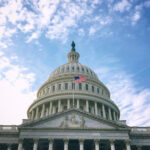capitol-dome-american-flag-on-clear-blue-day