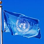 U 1 un-flag-flying-pole-blue-sky-behind-it